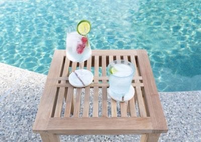 A refreshing drink on a wooden tray by the swimming pool company's showcase poolside.
