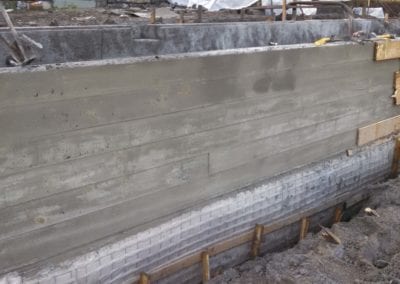 Newly poured concrete foundation wall for a swimming pool with wooden forms and reinforcing bars by a pool company.