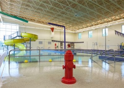Swimming pool company indoor swimming pool with a water slide and play features.