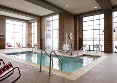 Indoor swimming pool area built by a reputable pool company, with large windows and brick walls.