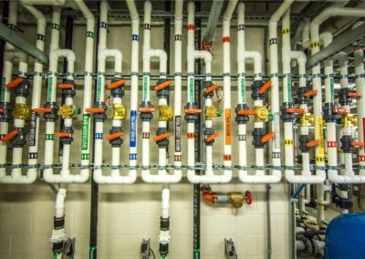 A network of organized industrial pipes and valves for a swimming pool company.