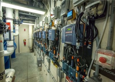 Electrical equipment and metering devices mounted on a wall in an industrial utility room by a swimming pool company.